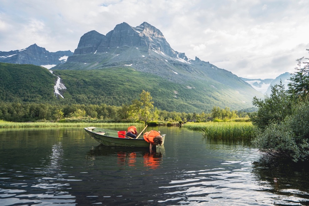 Children in a boat on a lake in front of mountain landscape